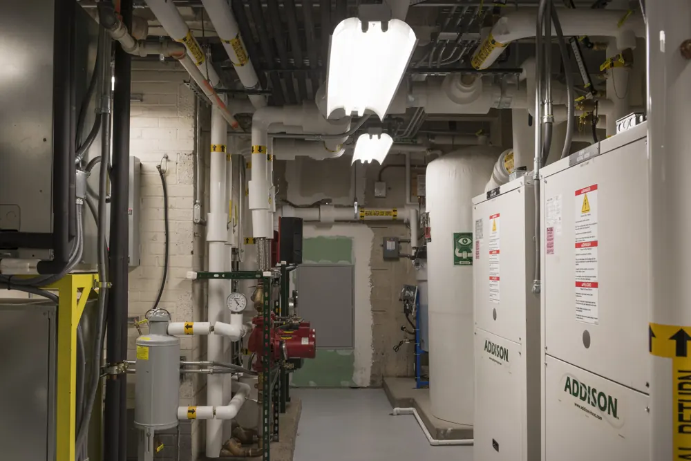White insulated pipes and a pump in the basement mechanical room of a federal building in Grand Junction, Colorado