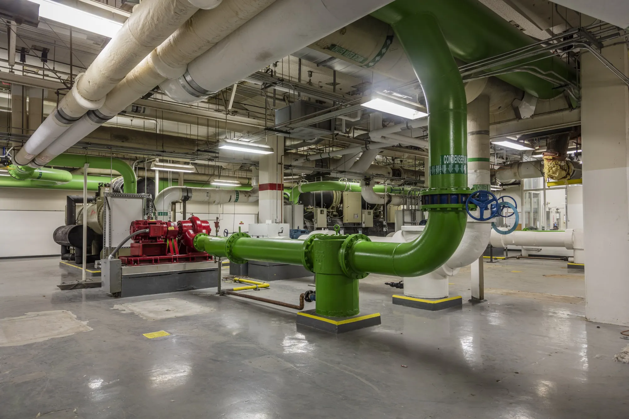 Green chilled-water pipes offsetting around a pump in a basement mechanical room