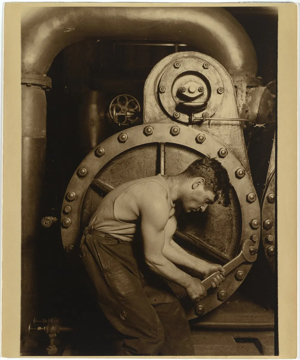 Lewis Hine, Steamfitter, 1921: a fitter bent over a wrench at a steam pump